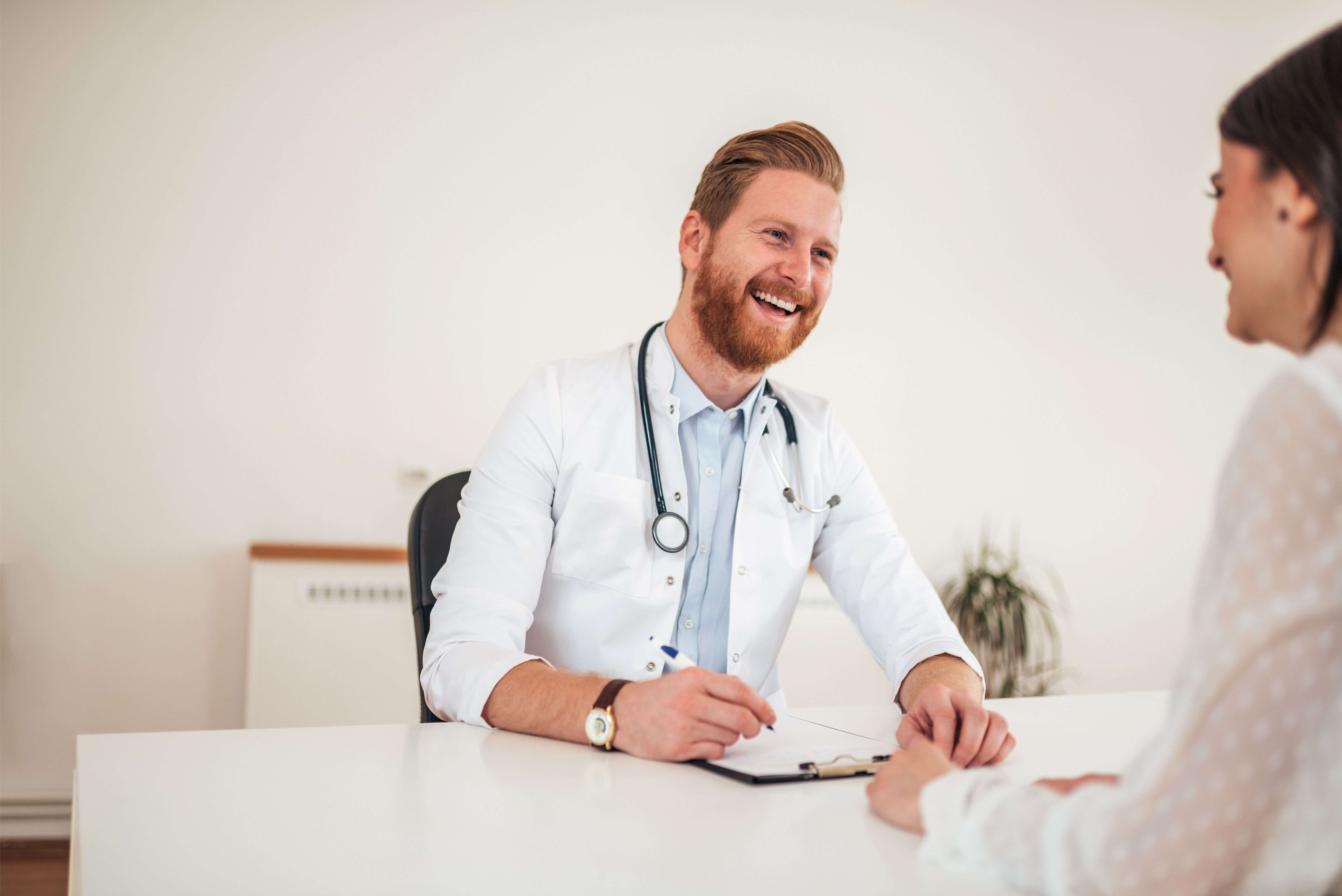 Cheerful doctor talking to patient in office.