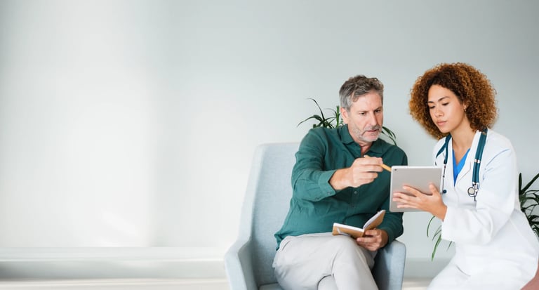 A healthcare professional in a white coat consults with a patient, using a tablet in a bright, modern office environment.