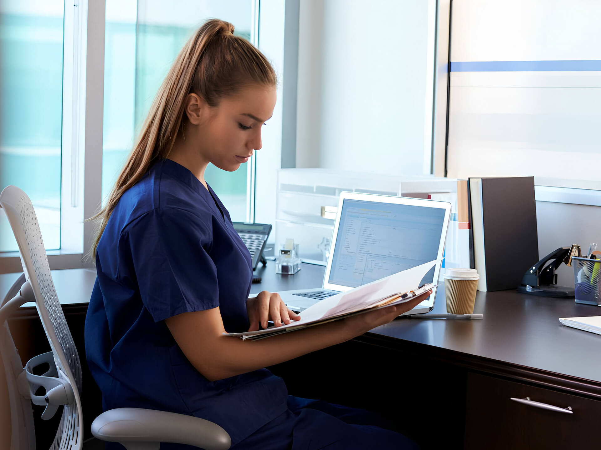 Young medical professional sitting at desk looking at paperwork