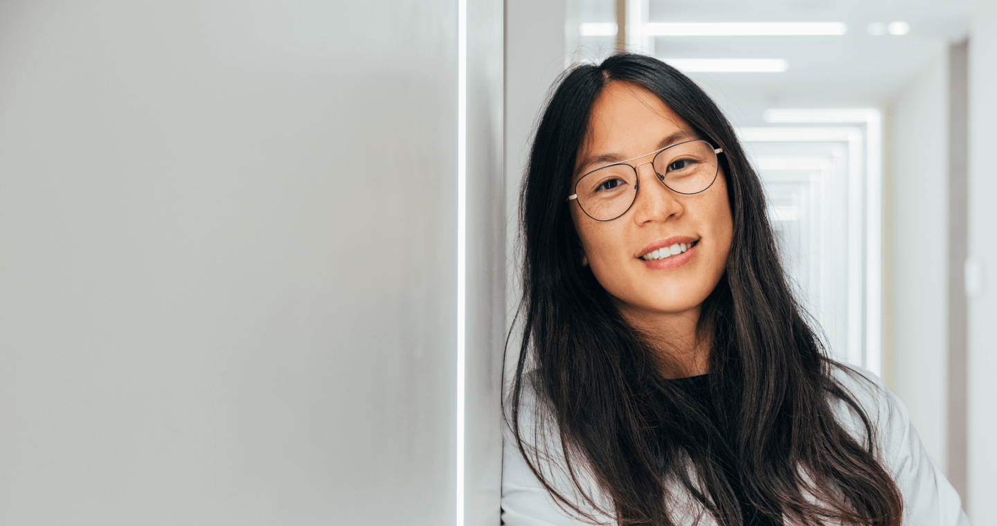 Asian woman doctor leaning against a wall.