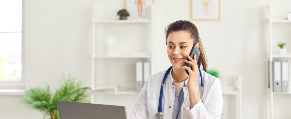 A woman in a white coat is talking on the phone, appearing engaged in conversation. 