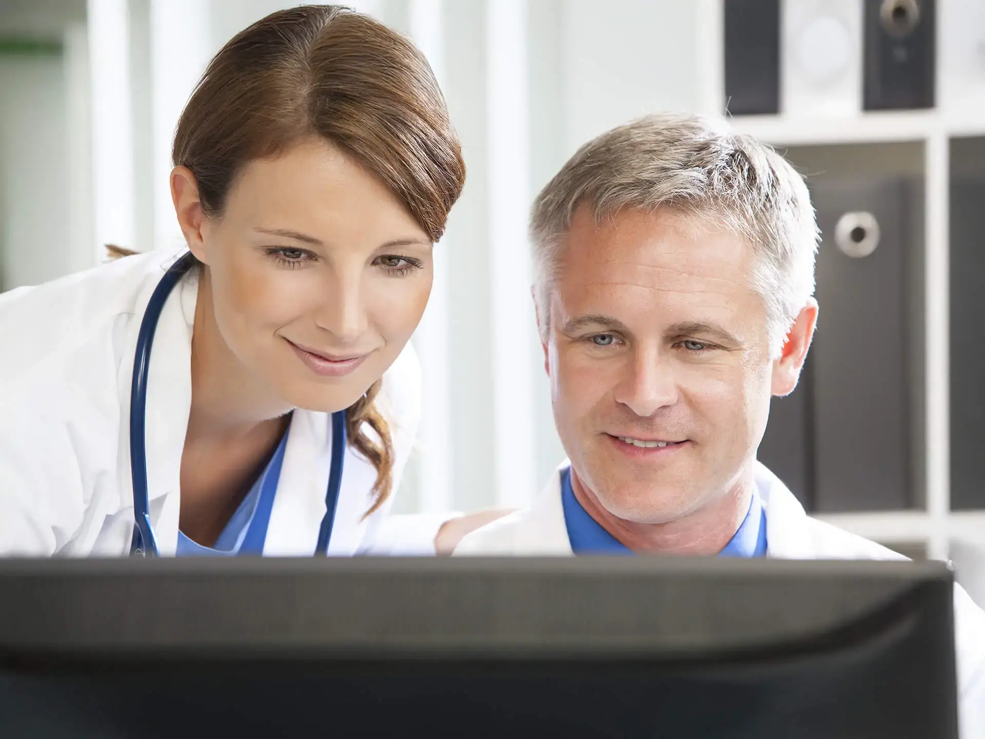 Female and male doctors looking at computer screen